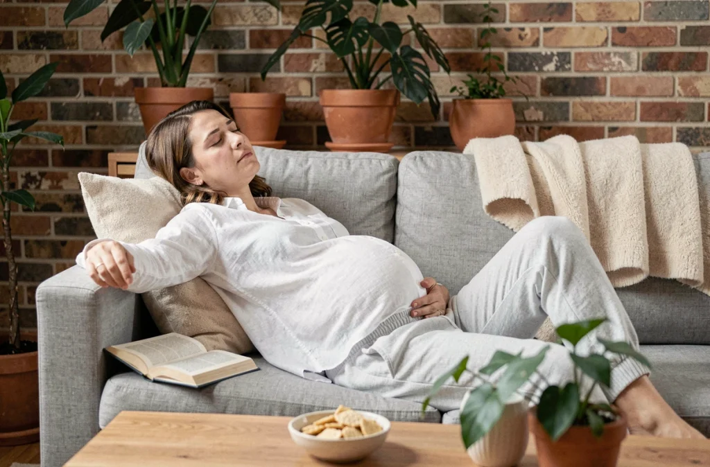 Femme enceinte se reposant sur un canapé avec des crackers à portée de main pour calmer les nausées du premier trimestre de grossesse